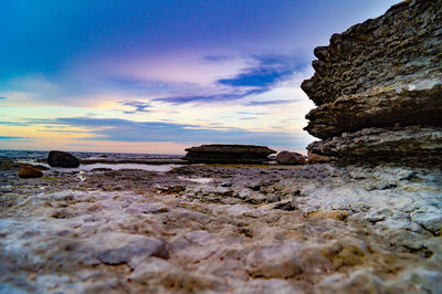 Surface level of rocks on shore against sky during sunset