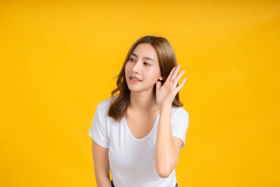 Portrait of smiling young woman against yellow background