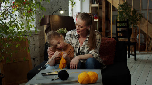 Side view of young woman sitting on table