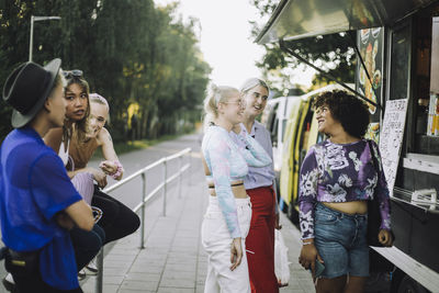 Smiling transgender woman talking with friends while standing by food truck