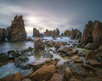 Rocks on sea shore against sky