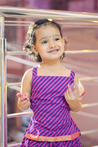 Girl smiling while standing against railing