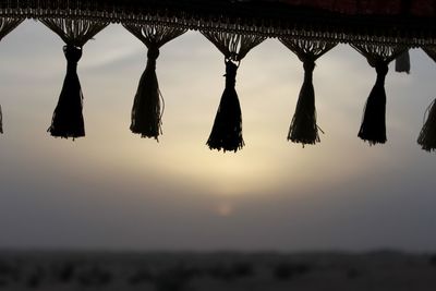 Low angle view of silhouette lanterns hanging against sky