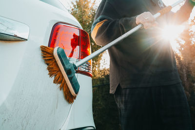 Manual car wash. man washes automobile with mop brush outside on territory of private house. 