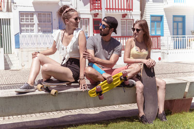 Portrait of smiling friends sitting on street