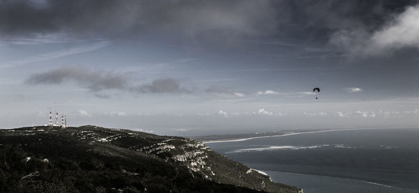 Scenic view of sea and mountain against cloudy sky