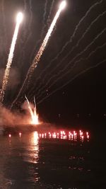 Firework display over river against sky at night