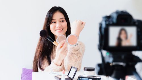 Portrait of a smiling young woman holding camera