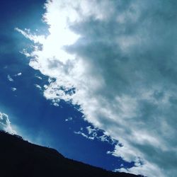 Low angle view of silhouette trees against blue sky