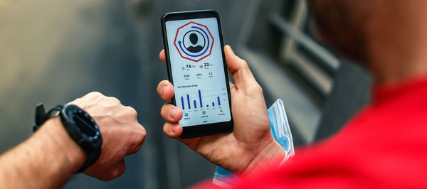 Close up of male hands using fitness app on smartphone man resting after jogging reading run results