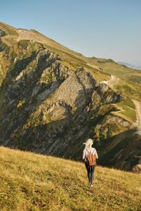 Rear view of woman walking towards mountain against sky