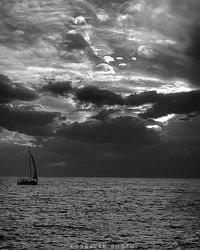 Boat sailing in sea against cloudy sky