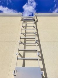 Low angle view of ladder by building against sky