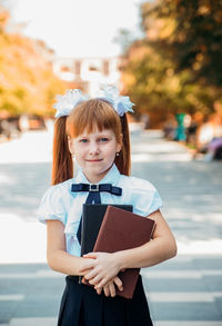 Funny charming little girl with books in her hands, on the first day of school or kindergarten.