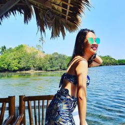 Young woman wearing sunglasses standing against sky