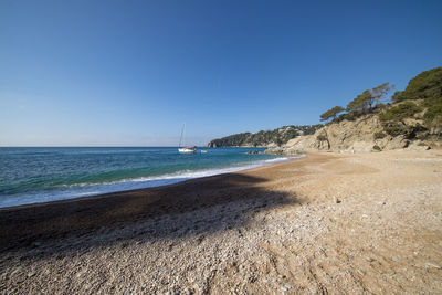 Scenic view of beach against clear blue sky