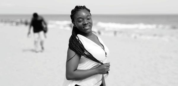 Portrait of woman standing at beach against sky