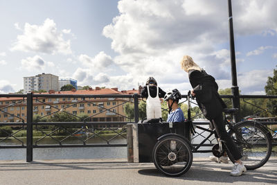 Mother riding bicycle with children in carriage