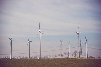 Windmills on field against sky