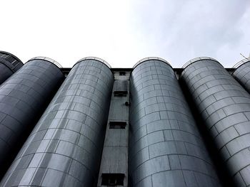 Low angle view of industry against cloudy sky