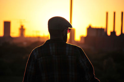 Rear view of man standing against sky during sunset