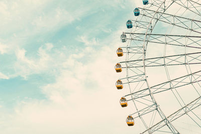 Low angle view of ferris wheel against cloudy sky