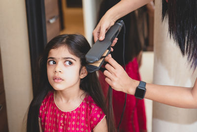 Hairdresser straightening the hair of girl 