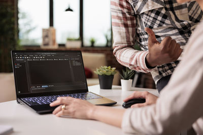 Midsection of man using laptop on table