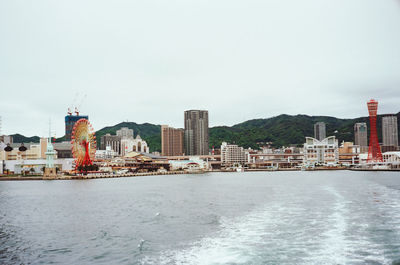 Sea by buildings against clear sky