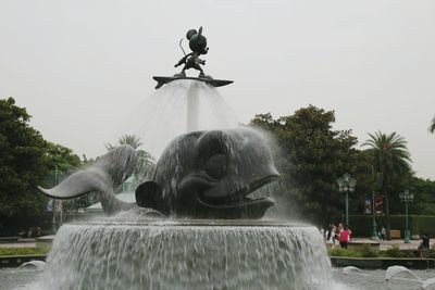 Statue by fountain against sky