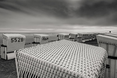 Hooded chairs on beach against sky