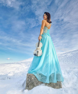 Woman standing on snow covered landscape against sky