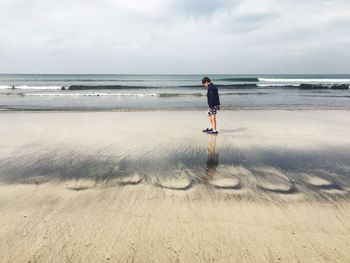 Side view of boy standing against sea at beach