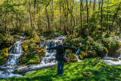 Full length of woman standing by plants in forest