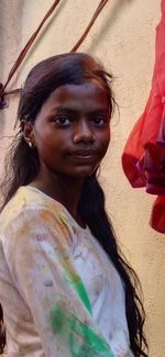 Portrait of smiling young woman standing against wall