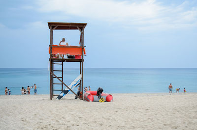 Tourists on beach against cloudy sky