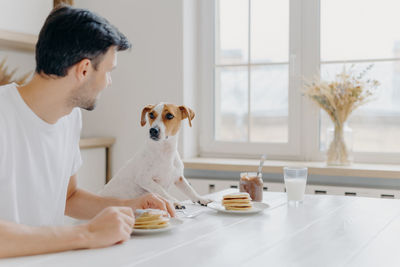 Man with dog sitting on table at home