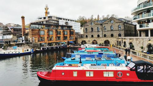 Boats moored in canal against buildings in city