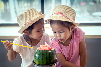 Close-up of twin sisters having drink in restaurant