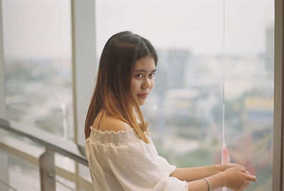 Side view of young woman looking away by window