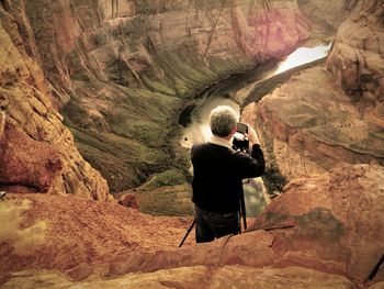 Rear view of man photographing at horseshoe bend