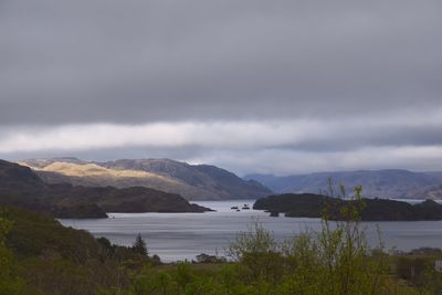 Scenic view of lake and mountains against cloudy sky