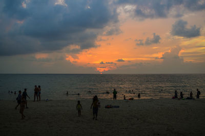 People on beach against sky during sunset