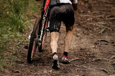 Low section of man with bicycle walking on dirt road