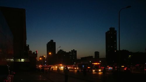 Illuminated city street against sky at night