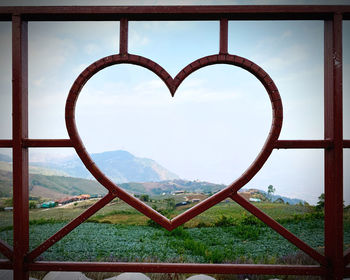 Close-up of heart shape on window against sky