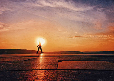 Silhouette person standing by sea against sky during sunset