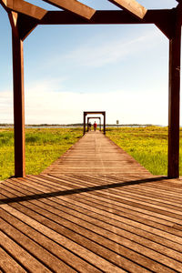 Empty wooden walkway along plants