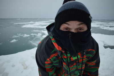 Portrait of man standing against sea during winter