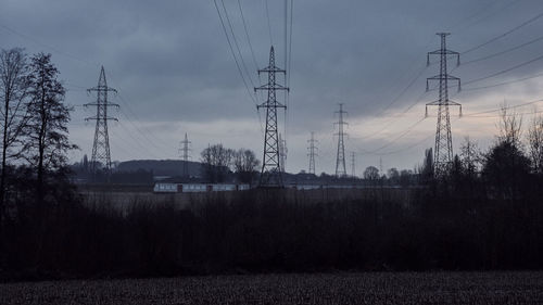 Electricity pylons on landscape against sky